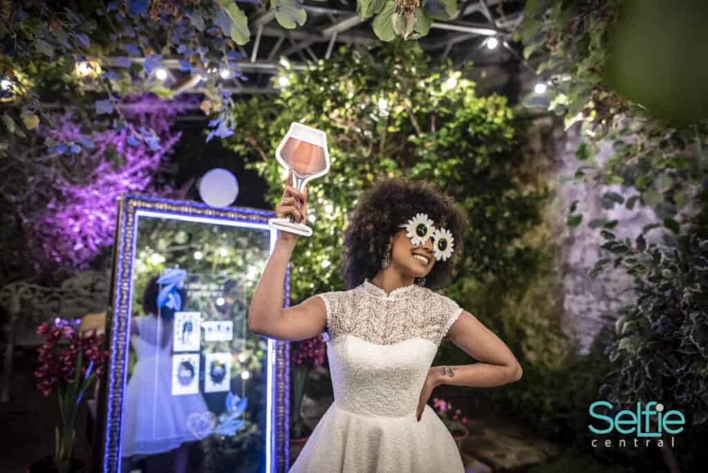 Woman with curly hair holding a lamp-shaped photo prop at Selfie Central in Auckland.