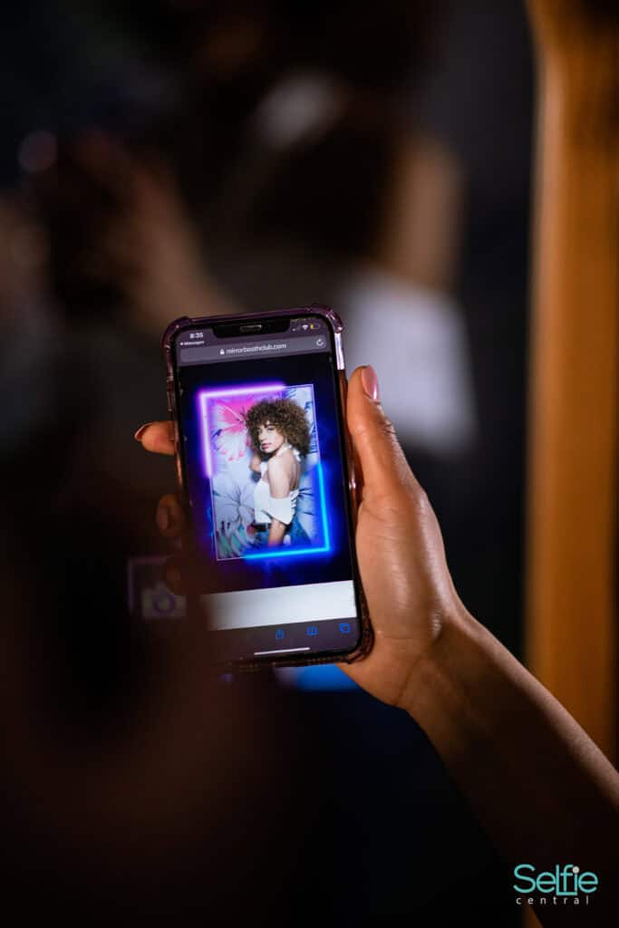 Person taking a selfie with a smartphone at a photo booth event in Auckland.