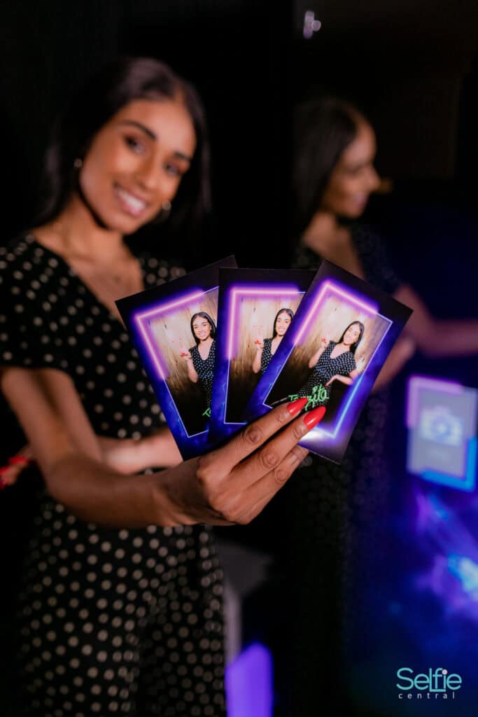 Woman holding selfie prints at Auckland photo booth event.