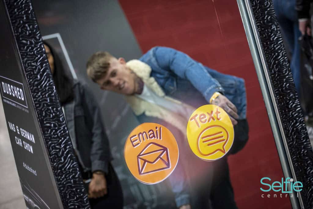 Woman using a photo booth with digital icons for email and text messaging in Auckland.