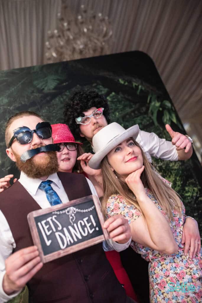 Group of friends enjoying a photo booth at an Auckland event with fun props and costumes.