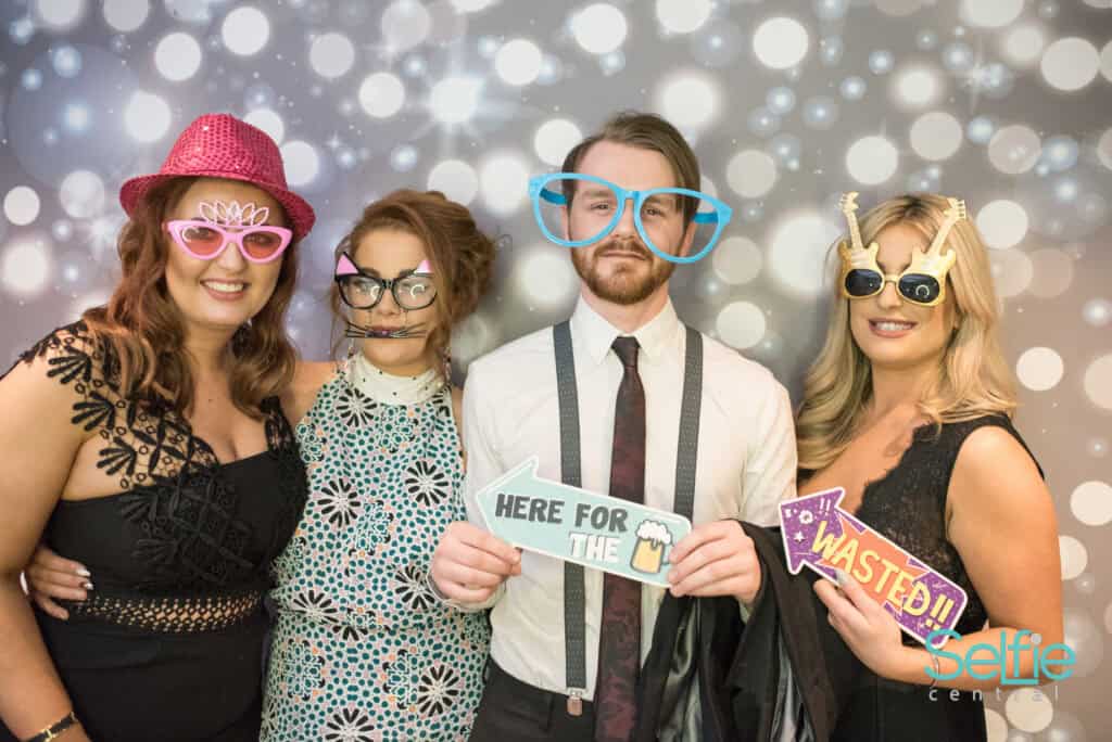Group of friends wearing colorful glasses and props at a photo booth in Auckland.