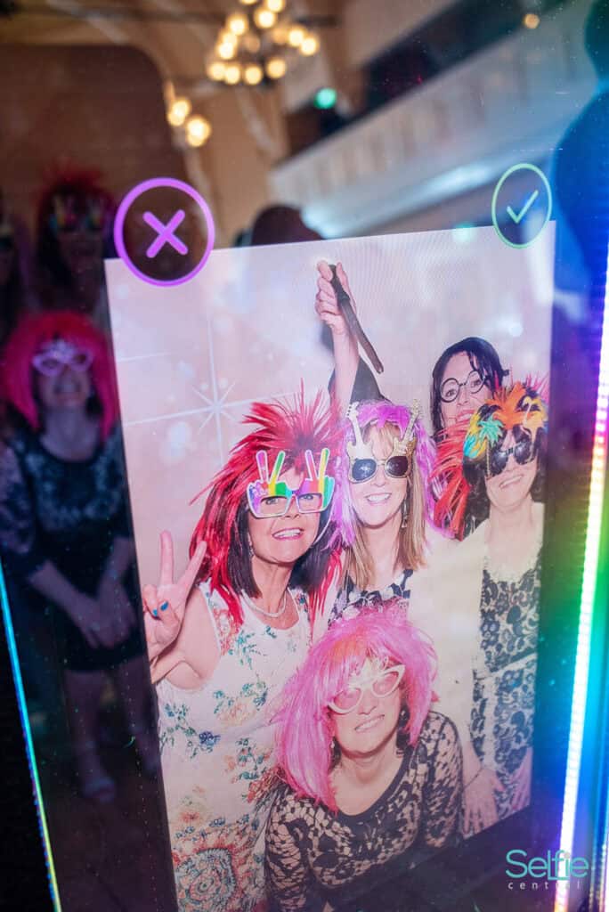 Group of women enjoying a photo booth with colorful props at an Auckland event.