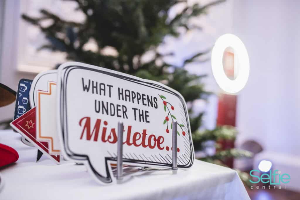 Christmas-themed photo booth sign with mistletoe message in Auckland.