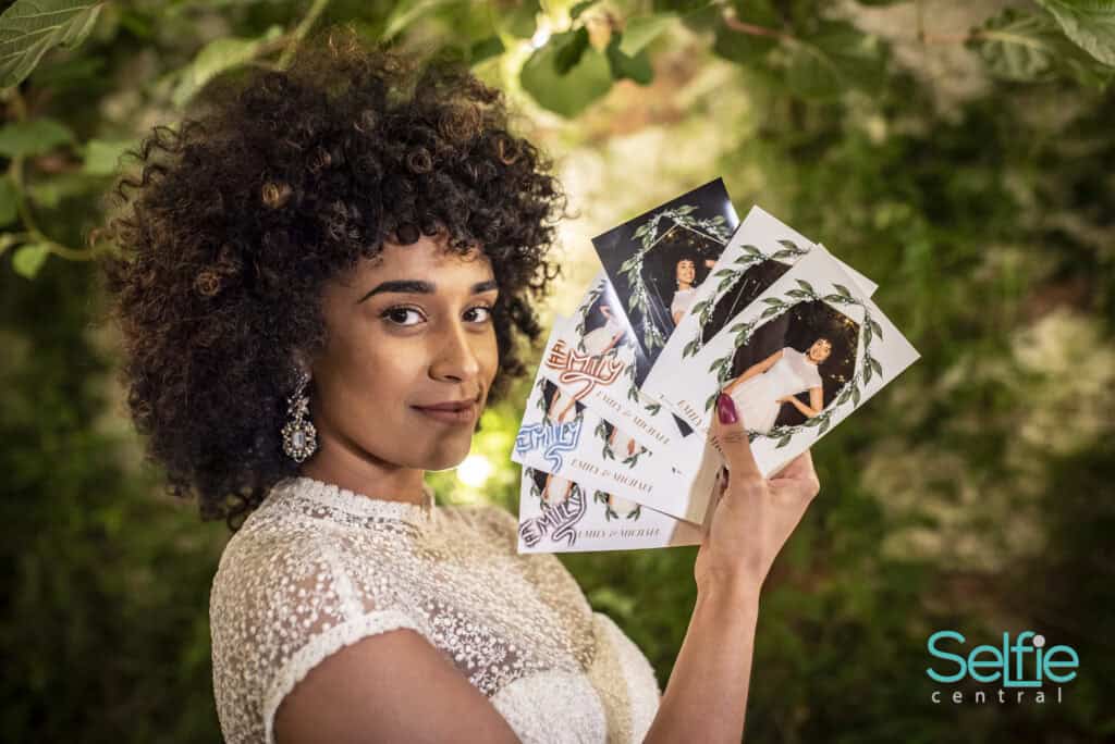 Woman holding printed photo booth pictures at Selfie Central Auckland.