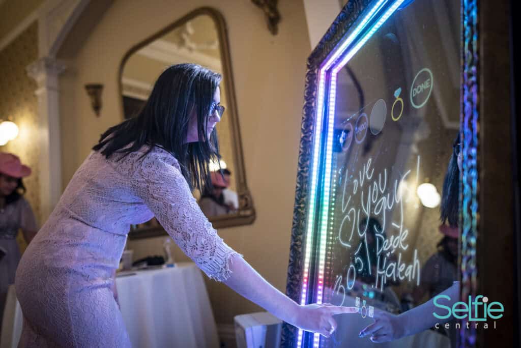 Woman using interactive photo booth at Auckland event with neon lights.